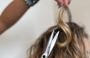 Parrucchiera mentre esegue un taglio di capelli ricci corti a una donna