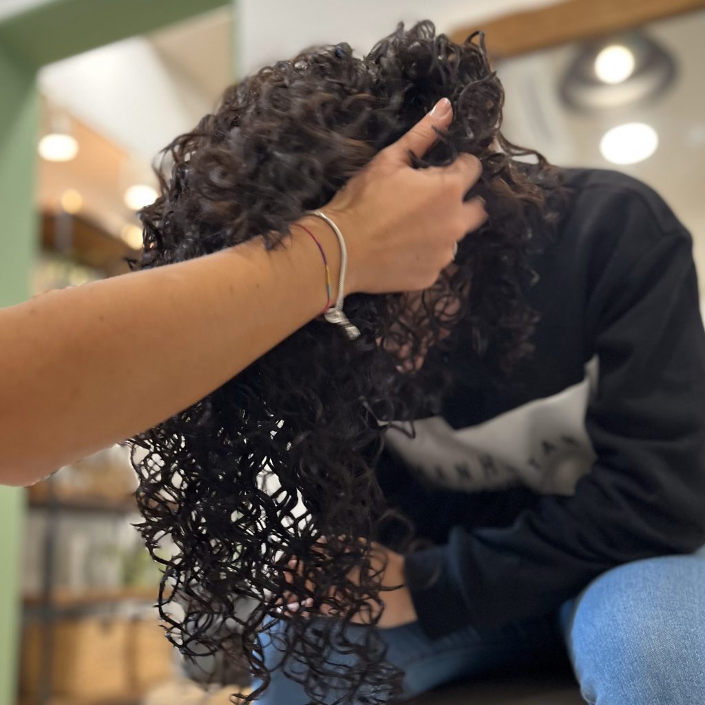 Donna in posa mentre parrucchiere effettua uno scrunch per controllo