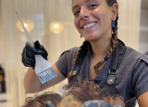 Parrucchiera professionista che applica una tinta colore a una donna in un salone di bellezza