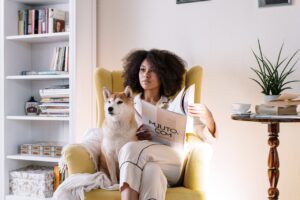 Donna con capelli ricci afro legge rivista seduta su poltrona