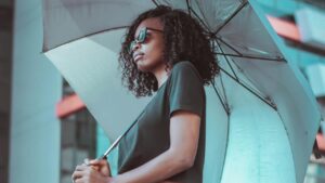 Donna con capelli ricci che si protegge dalla pioggia con ombrello