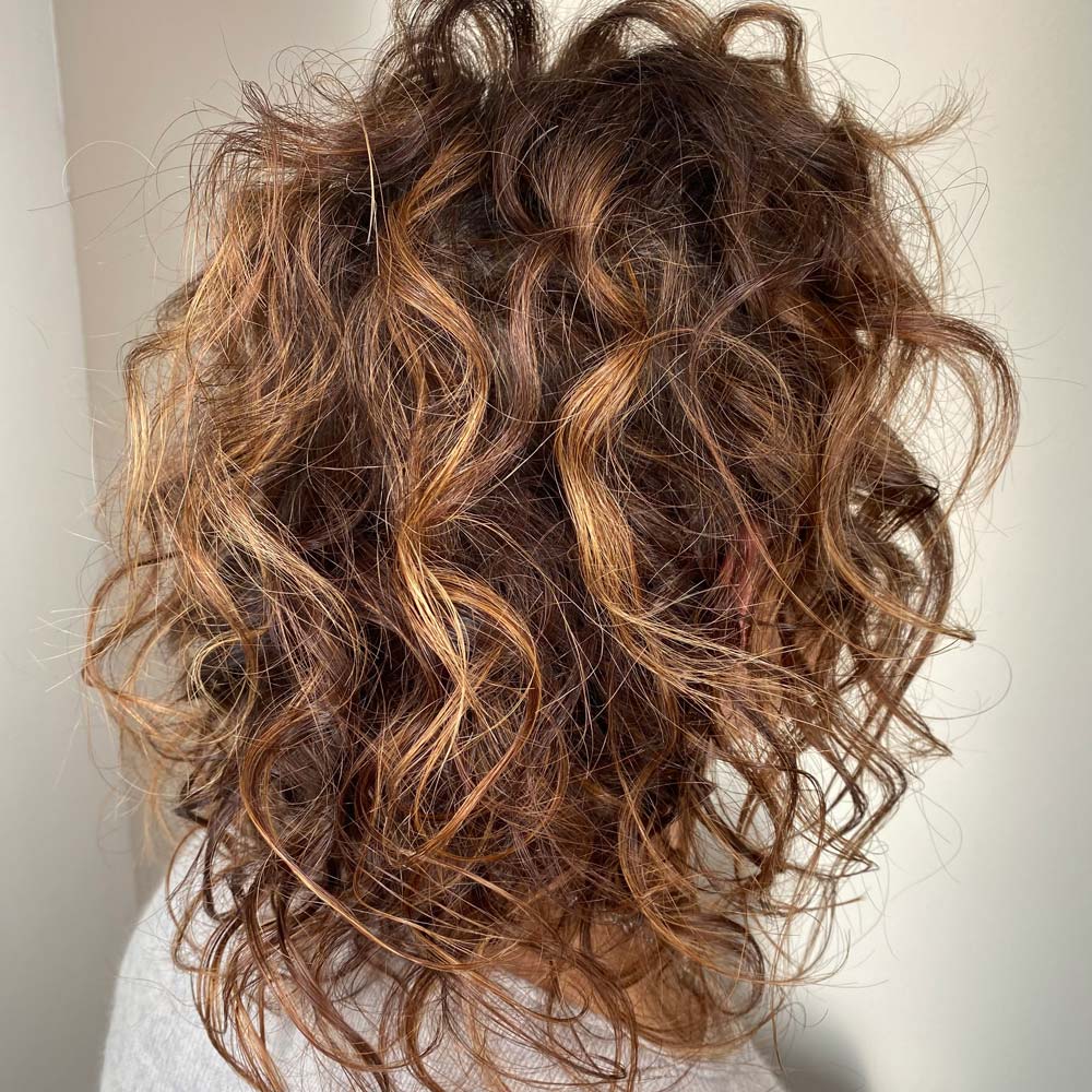Donna con capelli ricci curati con trattamenti e prodotti bio