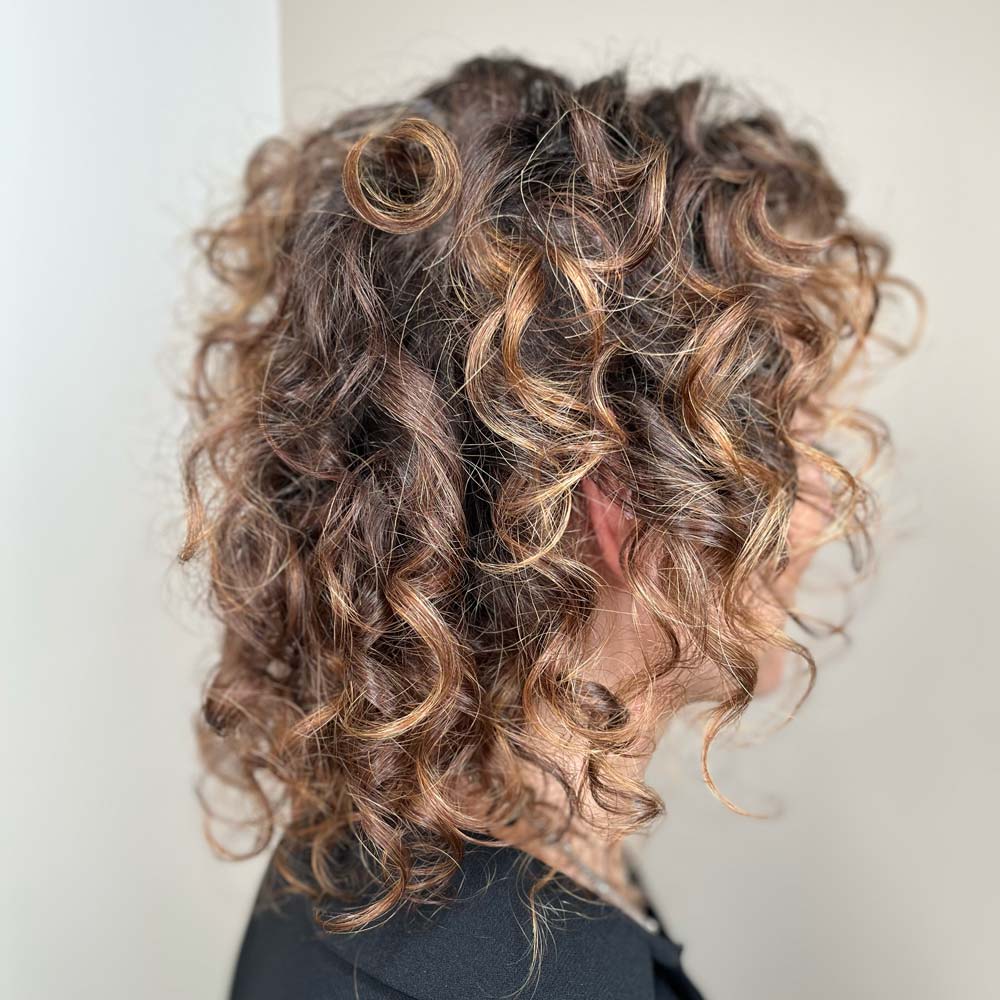 Donna con capelli ricci curati con trattamenti e prodotti bio