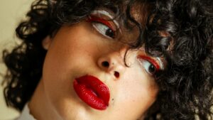 Donna con capelli ricci, trucco occhi rosso e bianco, labbra rosse