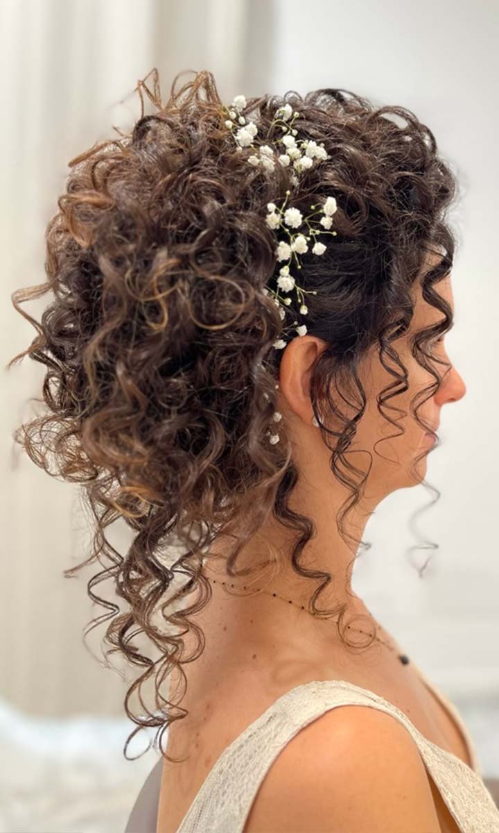 Sposa con acconciatura capelli ricci per matrimonio e decorazioni floreali