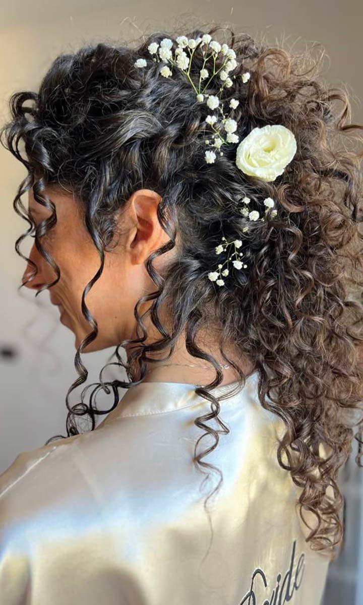 Sposa con acconciatura capelli ricci per matrimonio e decorazioni floreali
