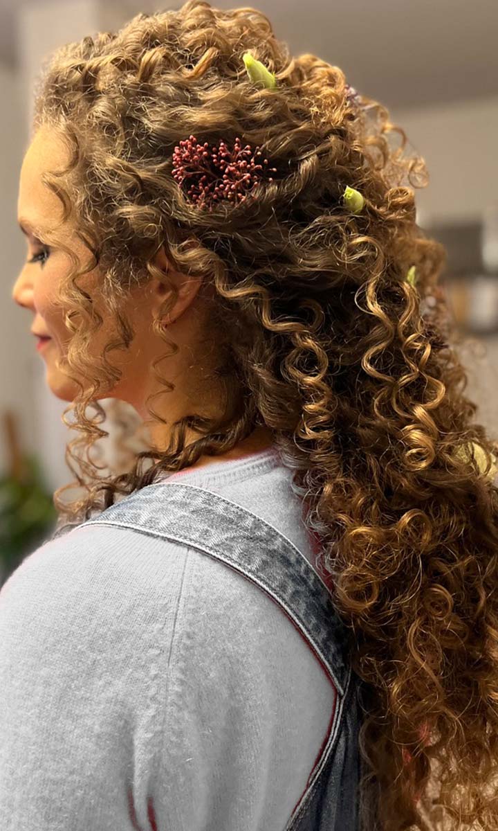 Acconciatura capelli ricci da sposa con decorazioni floreali