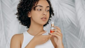 Donna con capelli ricci neri e flacone per la cura dei capelli