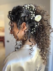 Sposa con capelli lunghi ricci e decorazioni floreali