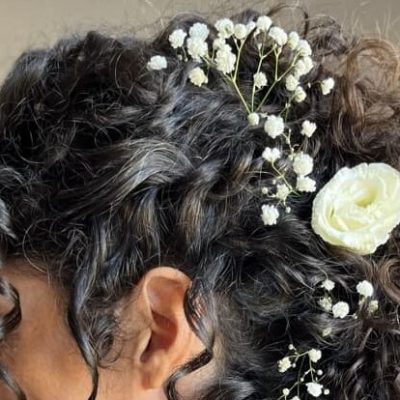 Donna con capelli ricci lunghi e piccoli fiori che le fermano l'acconciatura