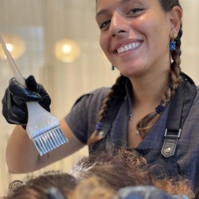 Parrucchiera professionista che applica una tinta colore a una donna in un salone di bellezza