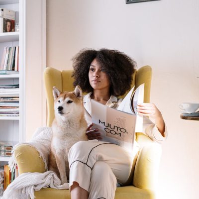 Donna con capelli ricci afro legge rivista seduta su poltrona