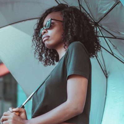 Donna con capelli ricci che si protegge dalla pioggia con ombrello