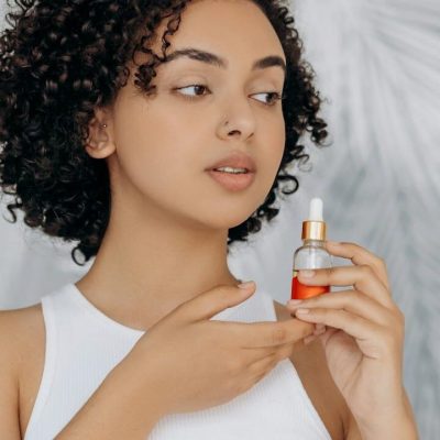 Donna con capelli ricci neri e flacone per la cura dei capelli