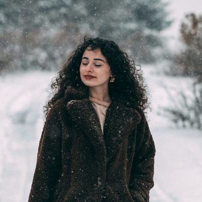Donna con capelli neri e ricci mentre nevica